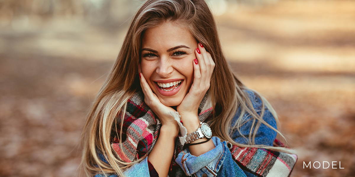 Model Smiles and Rests Her Chin on Her Hands While Outdoors